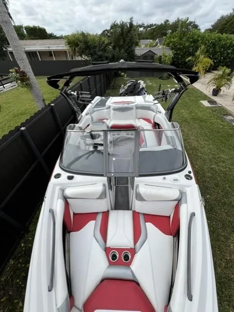 Slide: The Image of 2015 Tigé RZR boat with red and white interior, parked outdoors. - 6