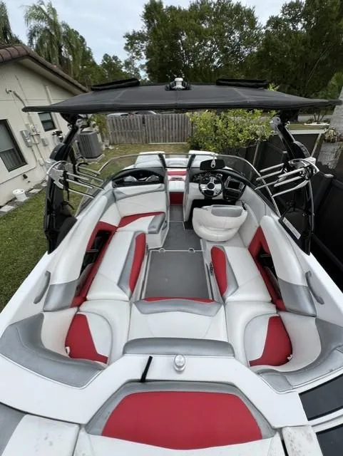 Slide: The Image of 2015 Tigé RZR boat with red and white interior, parked outdoors. - 7