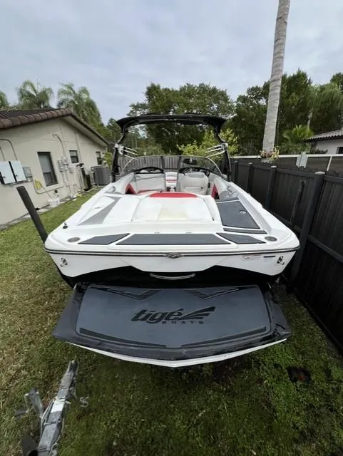Slide: The Image of 2015 Tigé RZR boat in backyard, white with black accents, near house and palm trees. - 9