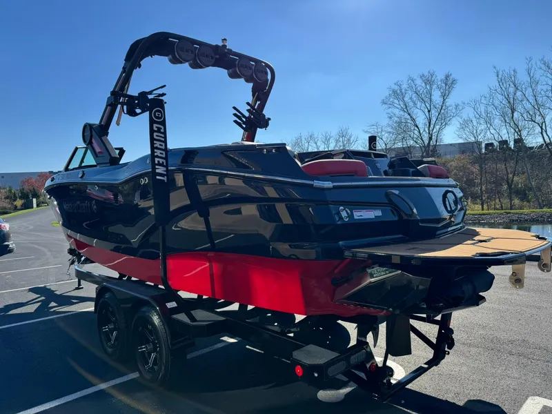 Slide: The Image of 2024 MasterCraft X24 boat on trailer, black and red design, parked outdoors. - 5