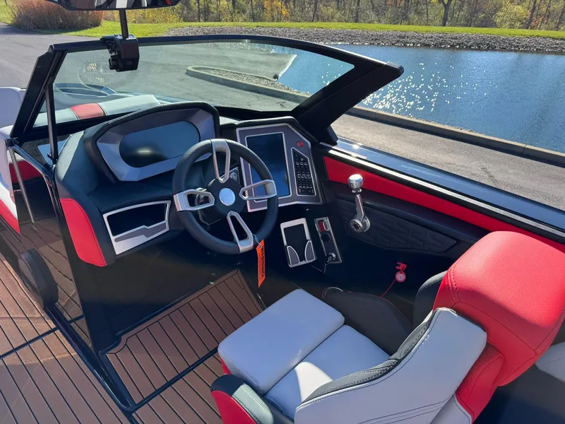 Slide: The Image of 2024 MasterCraft X24 boat interior with modern dashboard and steering wheel by the water. - 8