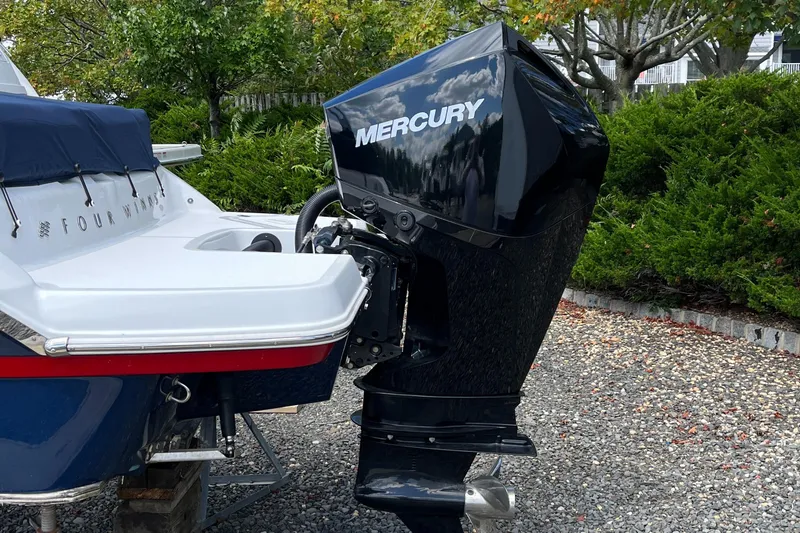 Slide: The Image of 2022 Four Winns H4 OB boat with Mercury outboard motor, parked on gravel. - 3