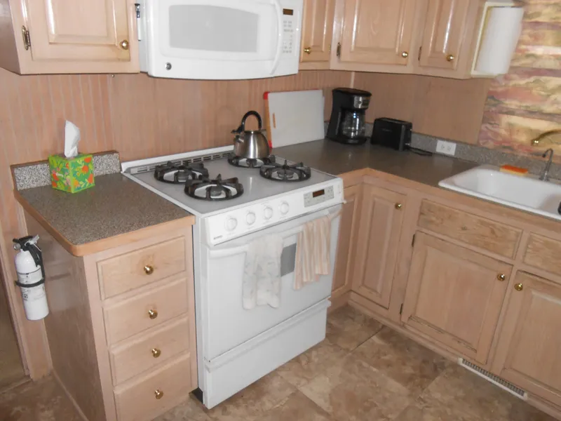 Slide: The Image of 1999 Horizon houseboat kitchen with stove, microwave, and wooden cabinets. - 15