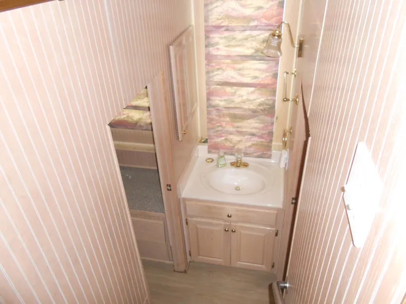 Slide: The Image of Compact bathroom in 1999 Horizon houseboat with sink, mirror, and striped wallpaper. - 21