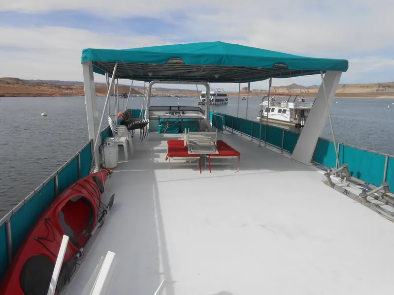 Slide: The Image of 1999 Horizon houseboat with spacious deck, canopy, and kayaks on a calm lake. - 26