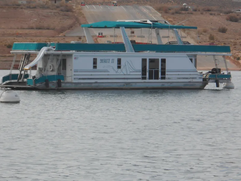 Slide: The Image of 1999 Horizon houseboat on calm water with slide and teal accents. - 4