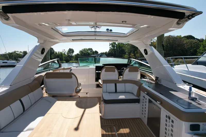 Slide: The Image of 2019 Sea Ray SLX 400 boat interior with wooden table and seating, docked by a serene lake. - 9