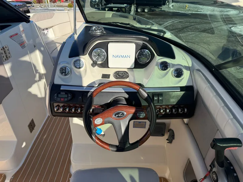 Slide: The Image of 2005 Sea Ray 270 SLX boat dashboard with Navman display and wood-accented steering wheel. - 10