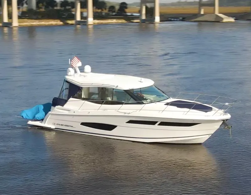Slide: The Image of 2022 Regal 38 Grande Coupe yacht cruising on a calm river with bridge in background. - 1