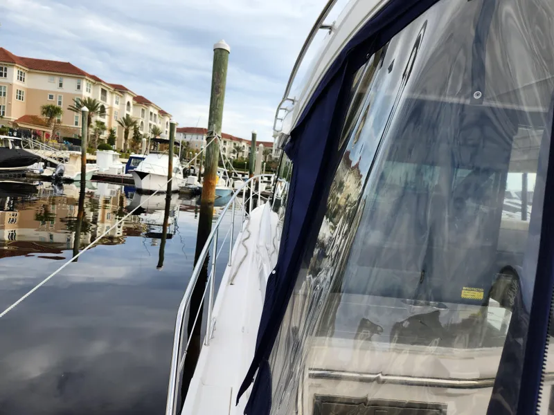 Slide: The Image of 2022 Regal 38 Grande Coupe docked at marina, reflecting calm waters and nearby buildings. - 11