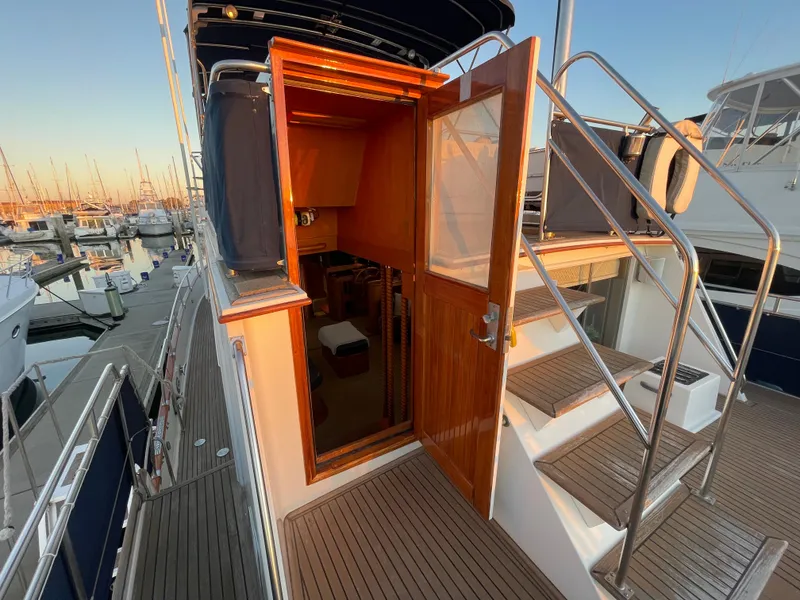Slide: The Image of 1995 Grand Banks 49 Motoryacht, exterior view with open cabin door and marina backdrop. - 19
