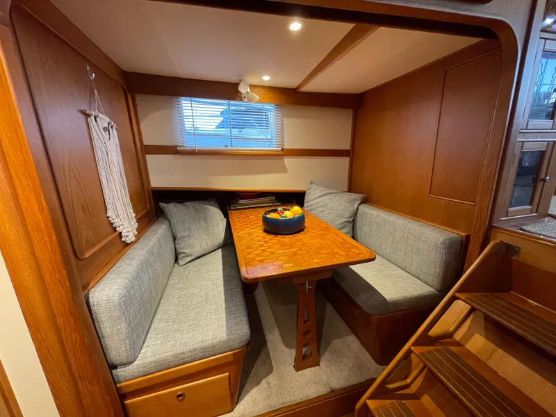 Slide: The Image of Cozy dining area in 1995 Grand Banks 49 Motoryacht with wooden table and cushioned seating. - 32