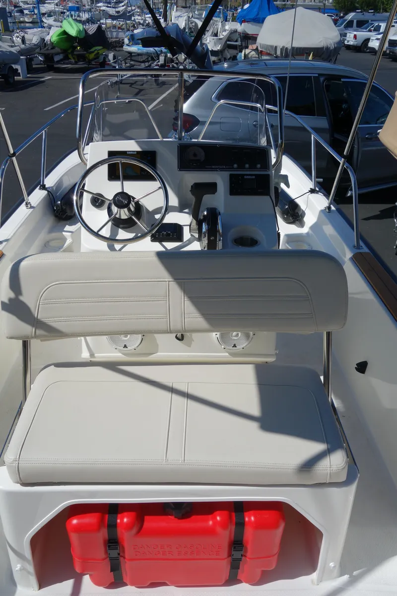 Slide: The Image of 2023 Boston Whaler 150 Montauk boat interior with steering wheel and seating. - 10