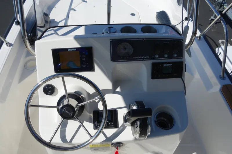 Slide: The Image of 2023 Boston Whaler 150 Montauk boat console with steering wheel and navigation controls. - 12