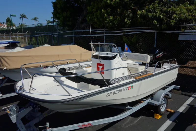 Slide: The Image of 2023 Boston Whaler 150 Montauk boat on trailer in parking lot. - 13