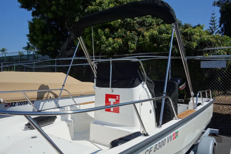 Slide: The Image of 2023 Boston Whaler 150 Montauk boat with canopy, parked outdoors. - 15