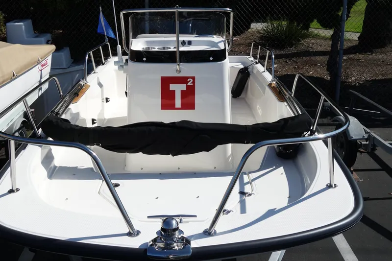 Slide: The Image of 2023 Boston Whaler 150 Montauk boat, white deck, stainless steel railings, docked outdoors. - 17