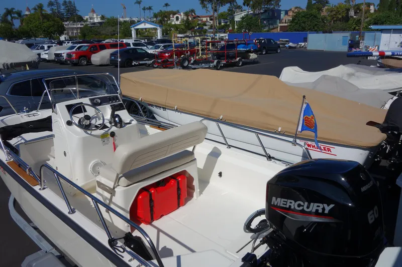 Slide: The Image of 2023 Boston Whaler 150 Montauk boat with Mercury engine in a marina setting. - 6