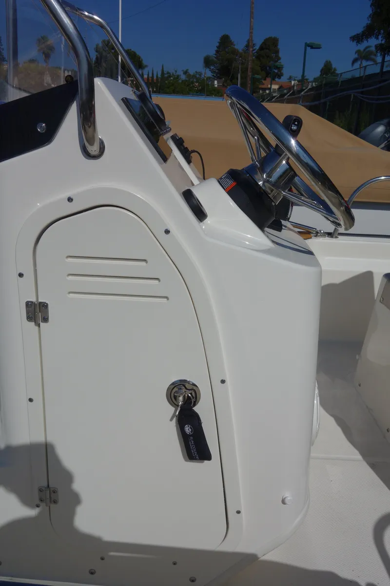 Slide: The Image of 2023 Boston Whaler 150 Montauk boat console with steering wheel and key. - 8