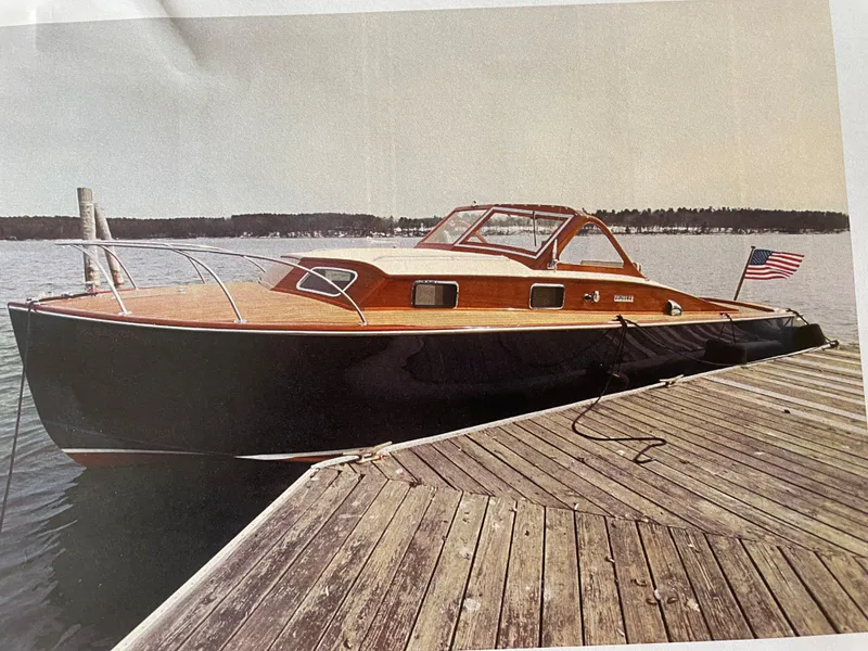 Slide: The Image of 1960 Prowler Semi-enclosed boat docked, featuring classic wooden design and American flag. - 11