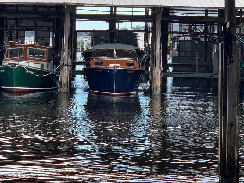 Slide: The Image of 1960 Prowler Semi-enclosed boat docked in a marina, surrounded by water and other vessels. - 14