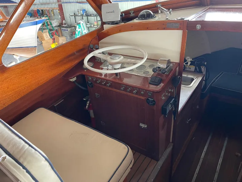 Slide: The Image of 1960 Prowler Semi-enclosed boat interior with wooden dashboard and white steering wheel. - 26