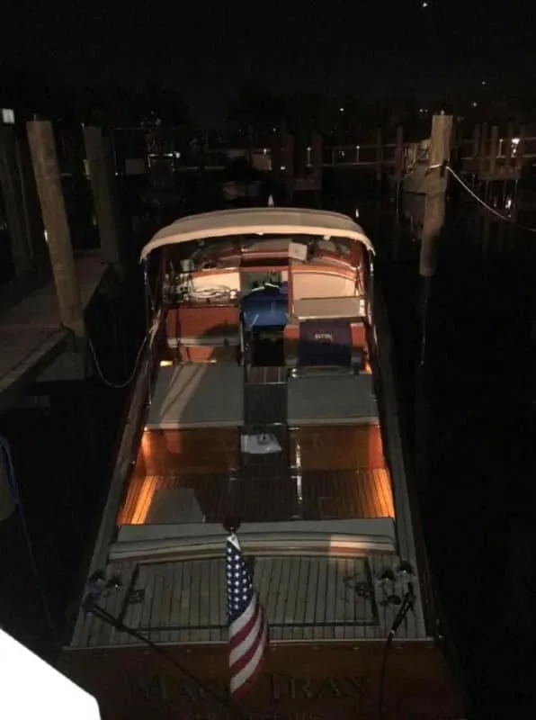 Slide: The Image of 1960 Prowler Semi-enclosed boat docked at night with illuminated interior and American flag. - 28
