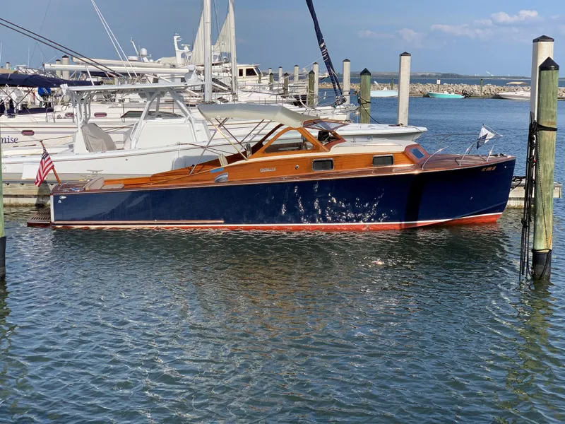 Slide: The Image of 1960 Prowler Semi-enclosed boat docked in marina, featuring classic wooden design and blue hull. - 5