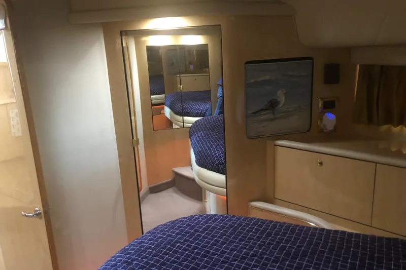 Slide: The Image of Interior of 2001 Sea Ray 400 Sedan Bridge with blue bedding and wooden cabinetry. - 37