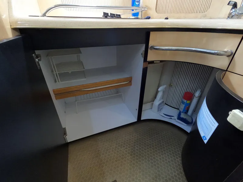 Slide: The Image of 2001 Sea Ray 400 Sedan Bridge kitchen cabinet with open storage and cleaning supplies. - 58