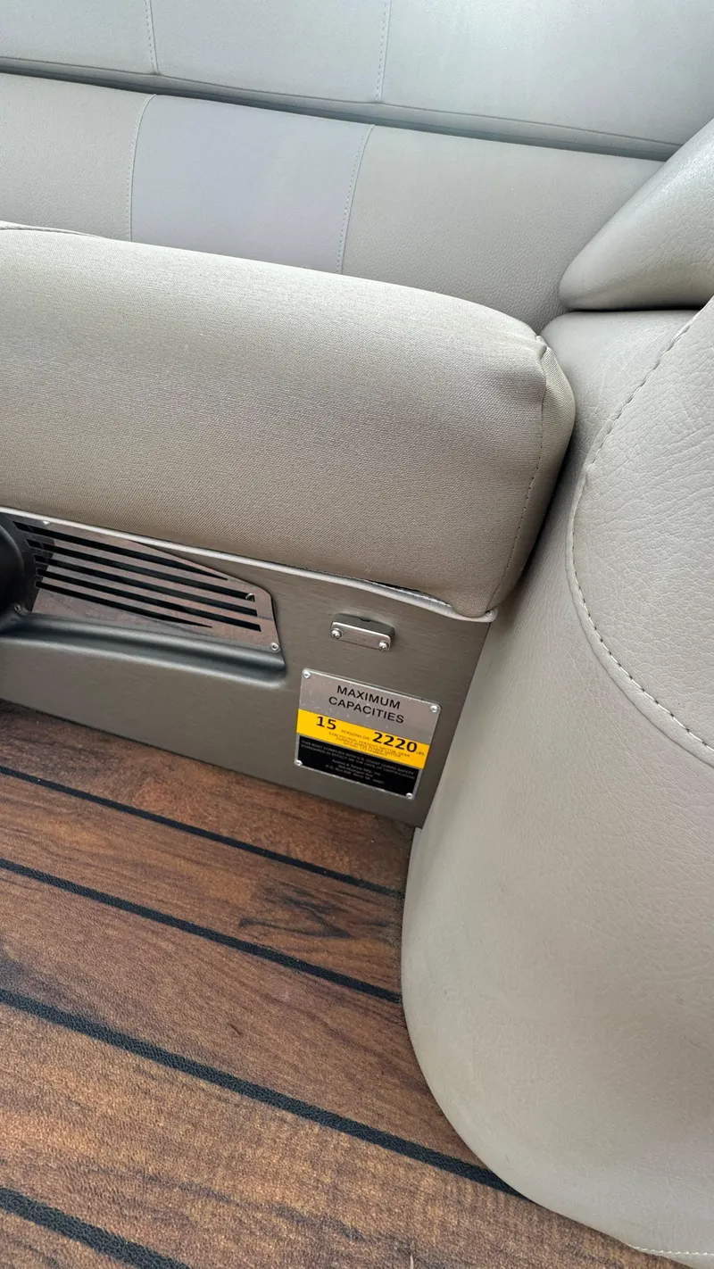 Slide: The Image of Avalon 2785 Paradise 2015 boat interior with capacity label, beige seating, and wood flooring. - 35