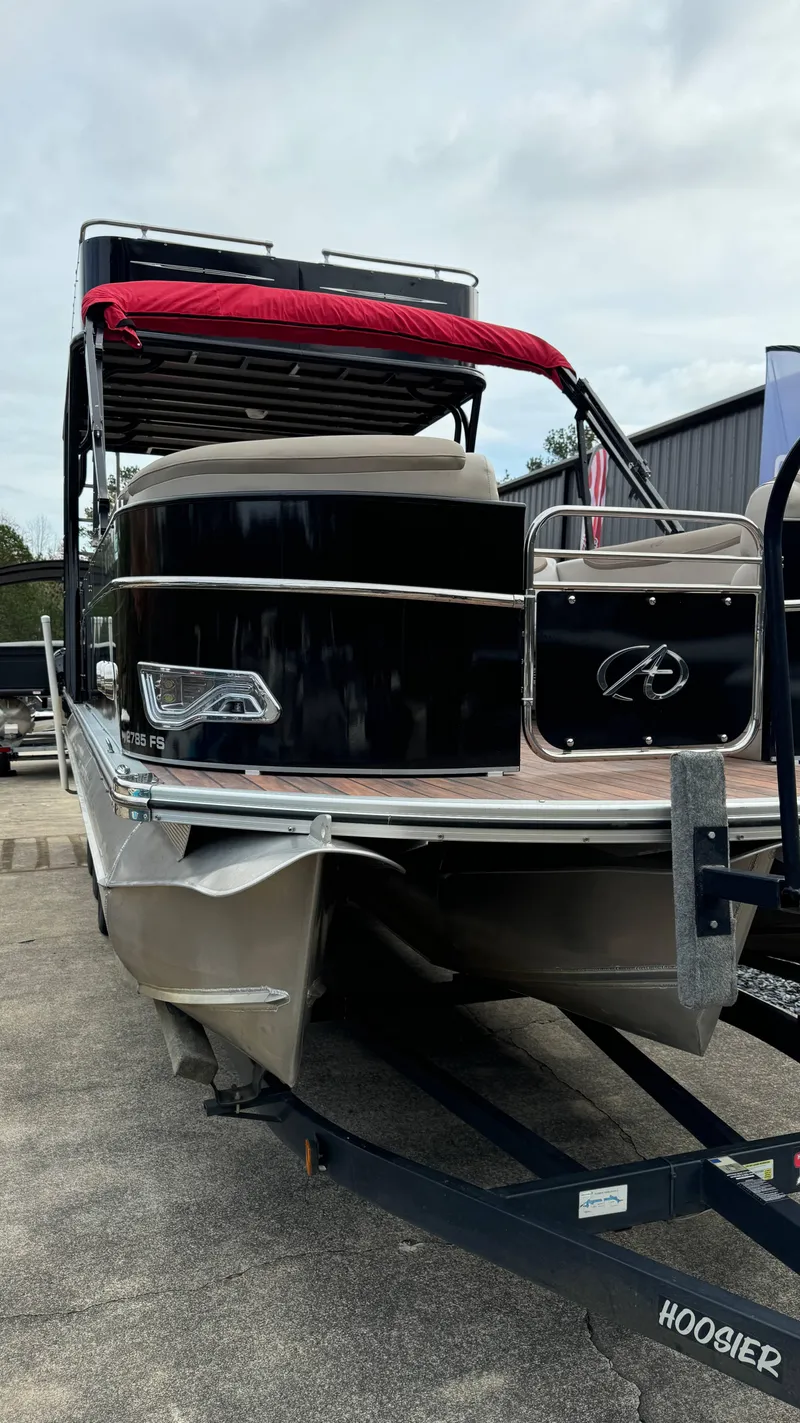Slide: The Image of 2015 Avalon 2785 Paradise pontoon boat on trailer, black exterior, red canopy. - 7