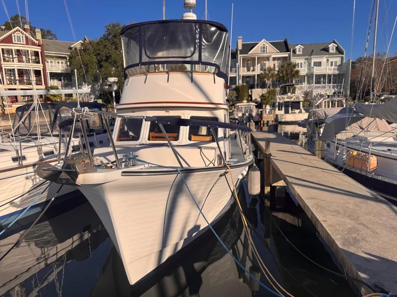 Slide: The Image of 1999 Monk 36 Trawler docked at marina with waterfront homes in background. - 1