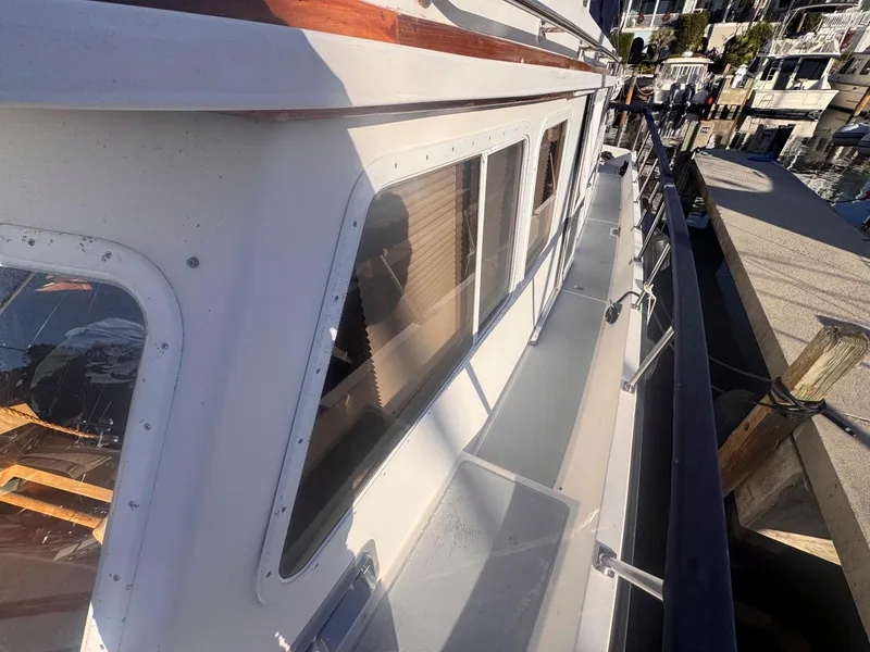 Slide: The Image of 1999 Monk 36 Trawler docked, showcasing side deck and windows. - 14