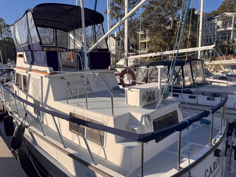 Slide: The Image of 1999 Monk 36 Trawler docked at marina, featuring spacious deck and canopy. - 2
