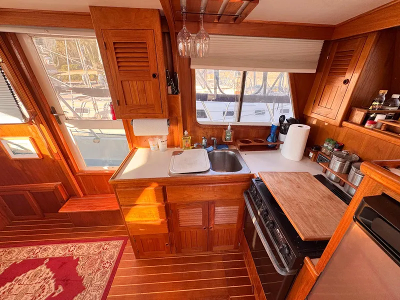 Slide: The Image of 1999 Monk 36 Trawler kitchen with wooden cabinetry, sink, stove, and window view. - 23