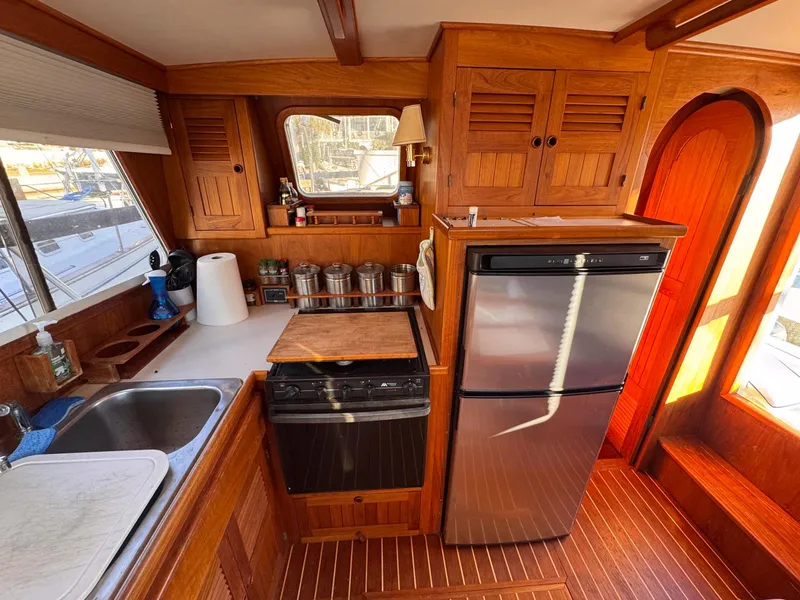 Slide: The Image of 1999 Monk 36 Trawler kitchen with wood cabinetry, stainless steel appliances, and ample counter space. - 24