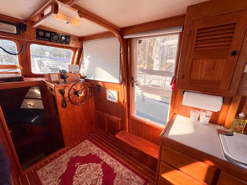Slide: The Image of Interior of 1999 Monk 36 Trawler with wooden helm, cozy seating, and nautical decor. - 25