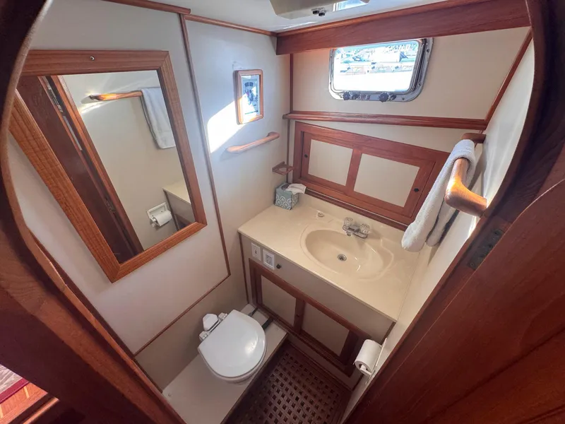 Slide: The Image of Bathroom interior of 1999 Monk 36 Trawler with wooden accents and porthole window. - 34