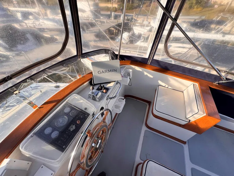 Slide: The Image of 1999 Monk 36 Trawler helm with Garmin navigation, featuring wood accents and seating. - 6