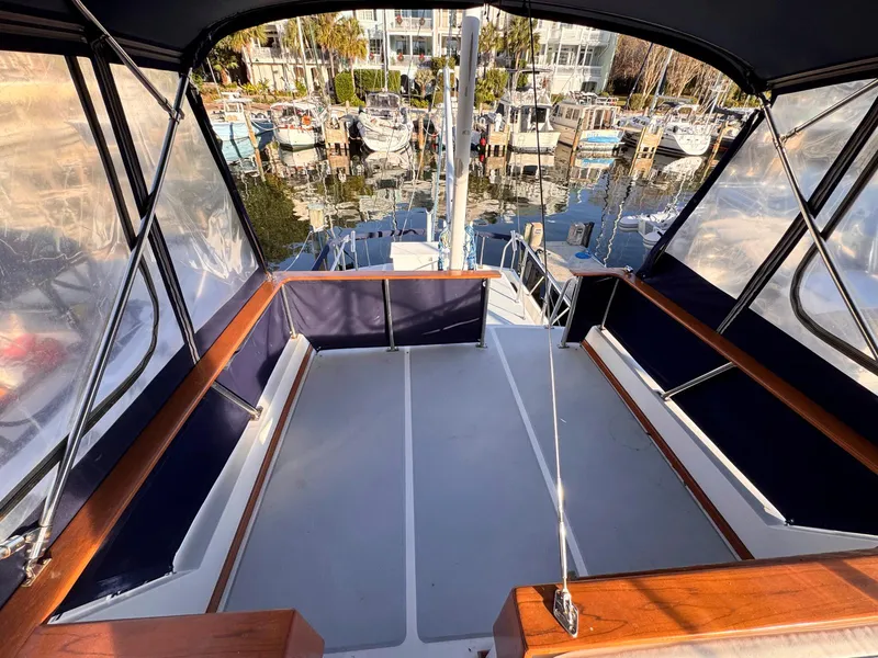 Slide: The Image of 1999 Monk 36 Trawler cockpit with marina view, featuring spacious seating and clear canopy. - 9