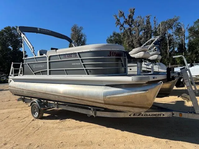The Image of 2022 Godfrey Sweetwater 2086 F pontoon boat on trailer, parked on sandy ground. - 0