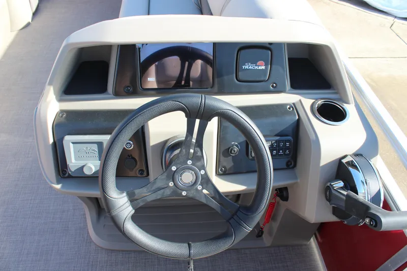 Slide: The Image of 2025 Sun Tracker Party Barge 22 DLX steering console with controls and cup holder. - 13