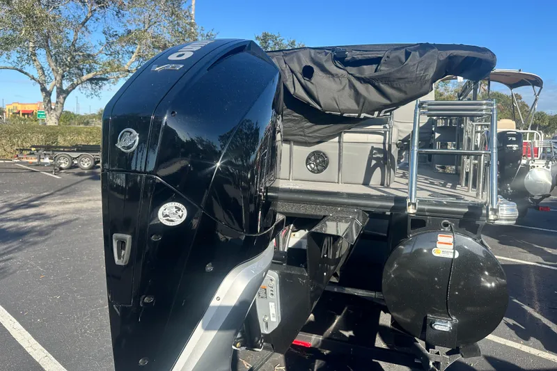 Slide: The Image of 2024 Regency R230LE3 SPT boat with powerful outboard motor in a sunny parking lot. - 2