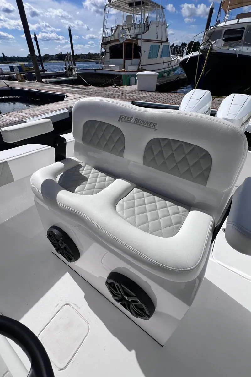 Slide: The Image of 2025 Reef Runner 280 boat with luxurious white seating and quilted design at marina. - 5