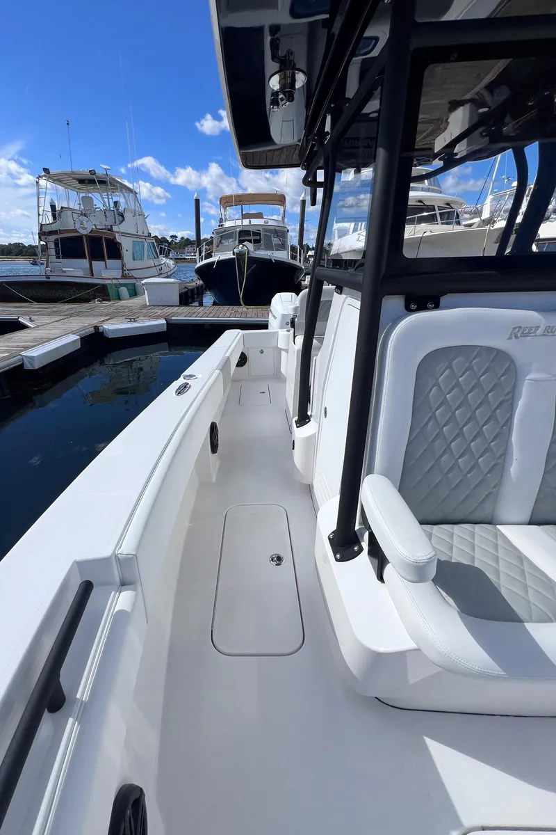 Slide: The Image of 2025 Reef Runner 280 boat docked, featuring sleek white design and comfortable seating. - 8