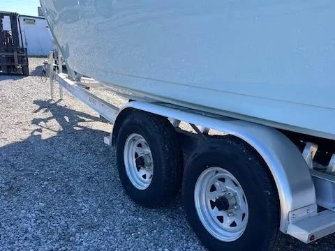 Slide: The Image of 2024 Sea Pro 240DLX boat on a dual-axle trailer, parked on gravel. - 14