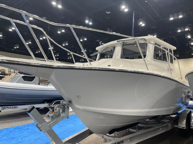 The Image of 2025 Defiance Admiral 250 EX boat on blocks beside a parked SUV. - 2