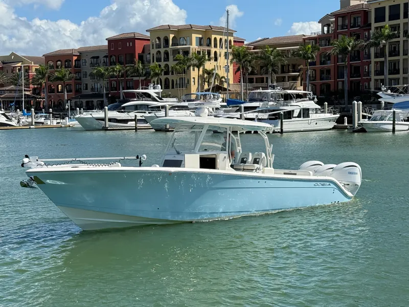 Slide: The Image of 2023 Cobia 350 Center Console boat docked in a marina with colorful buildings. - 2