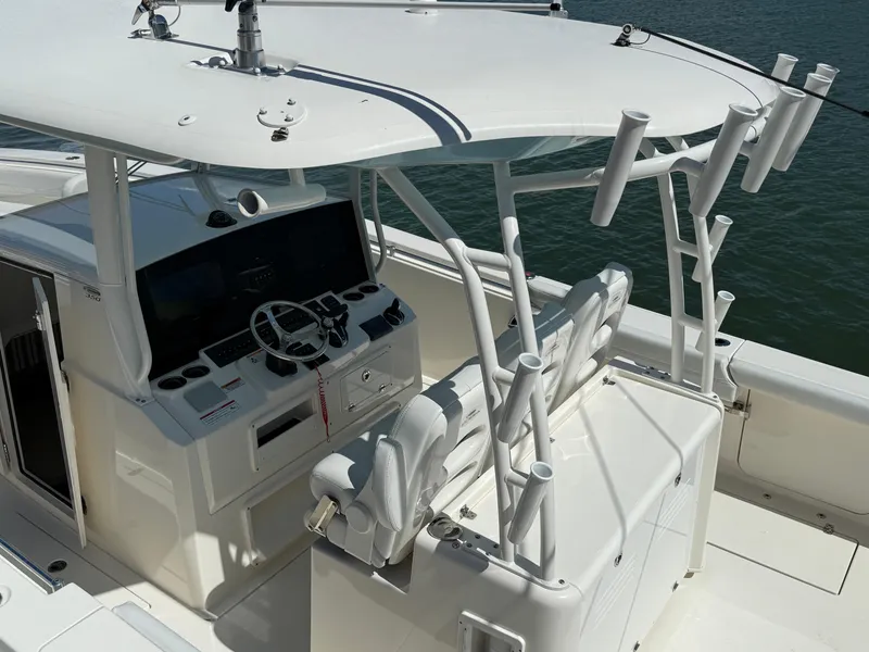 Slide: The Image of 2023 Cobia 350 Center Console boat interior with helm and seating, featuring rod holders. - 21
